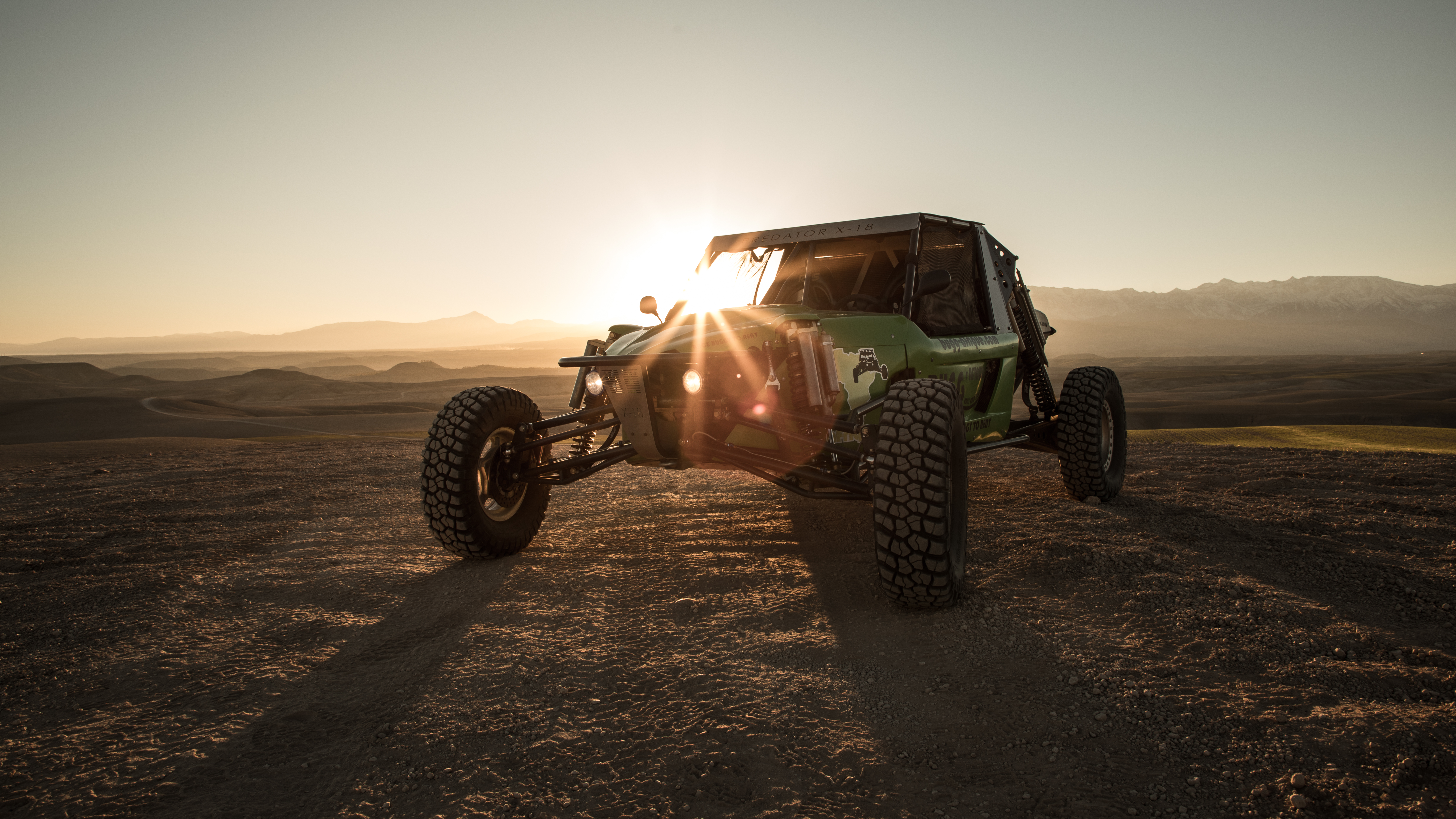 Dust trail across an empty dune field, golden hour.