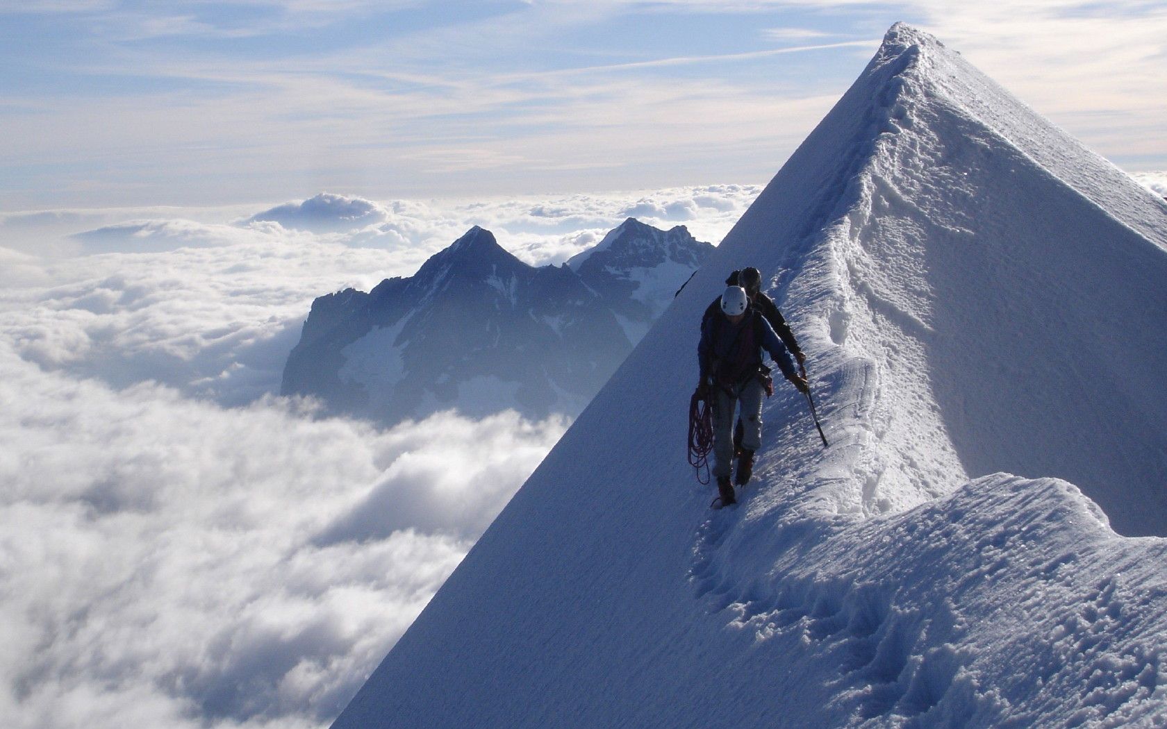 A lone figure on a knife-edge snow ridge above a sea of cloud